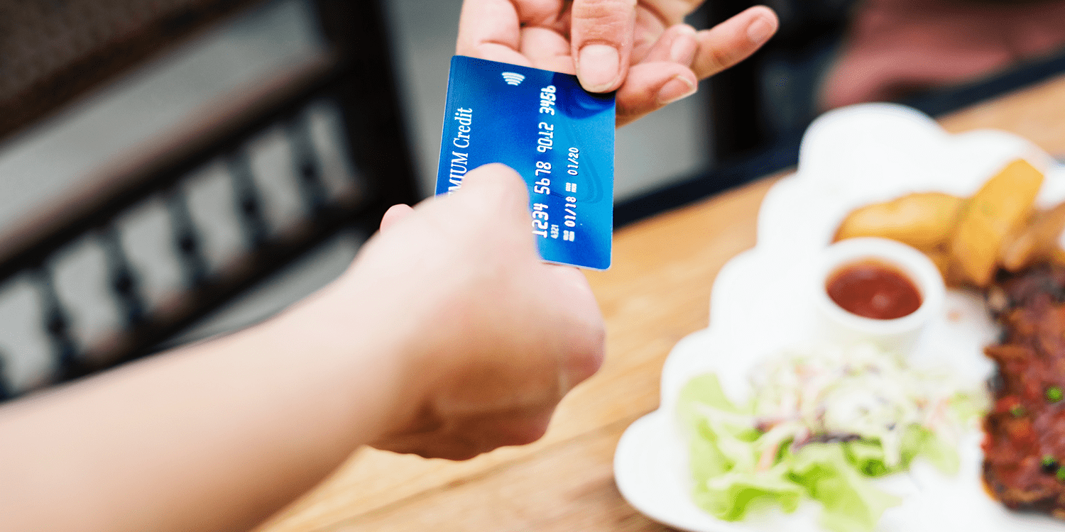 Image of a bank card being handed from one person to another, representing the concept of business bank accounts for non-UK residents.