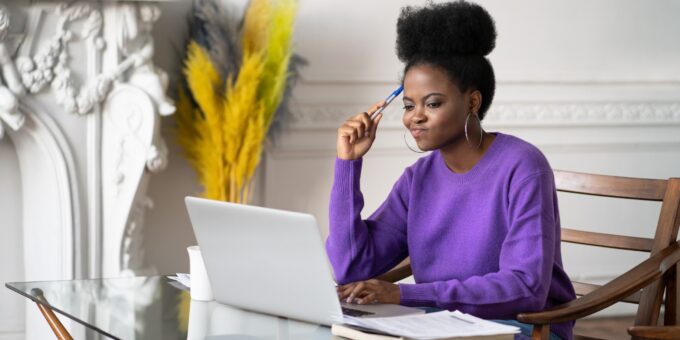 Woman at a laptop, pens in hand, researching whether she can use a dissolved company name.