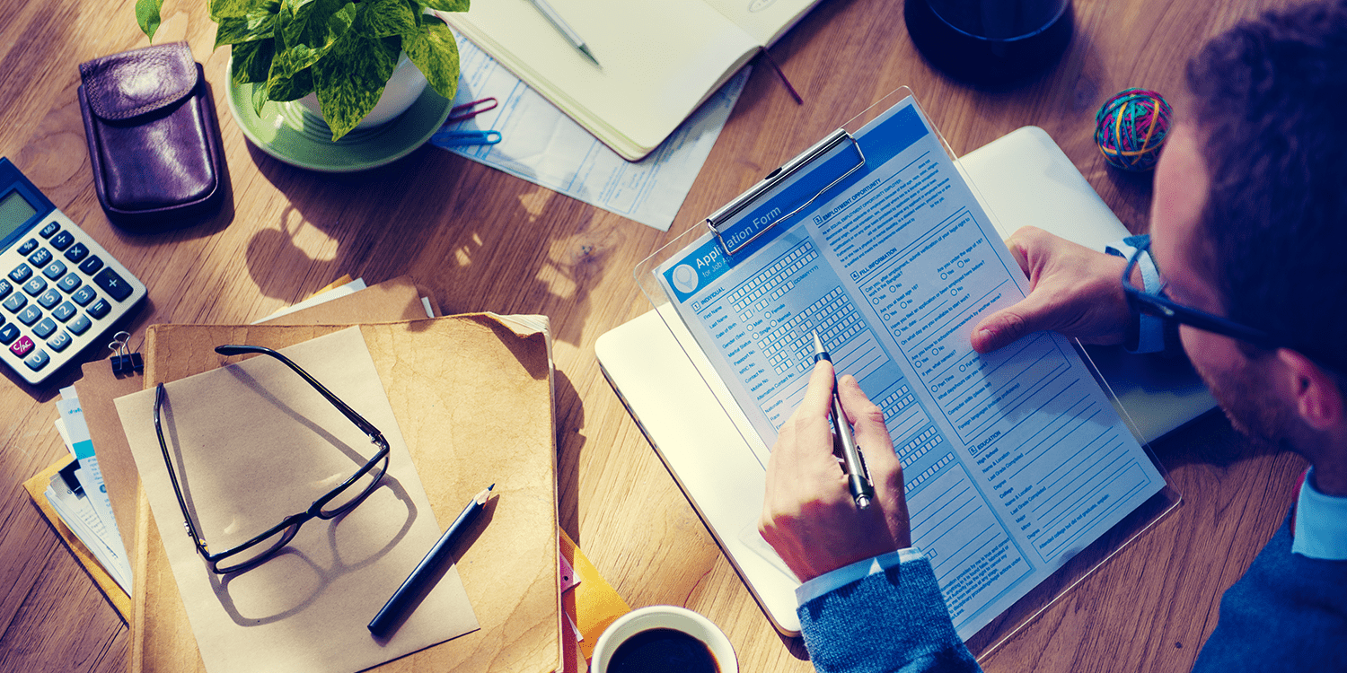 Image of a man sitting at a desk completing a detailed tax form, illustrating that Self Assessment for directors involves the completion and filing of a personal tax return.