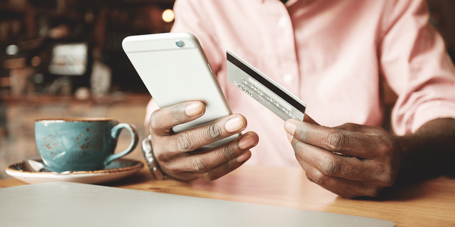 Image of a person holding a mobile phone in one hand and a bank card in the other, illustrating the ease of setting up a business bank account for a limited company and managing finances online.