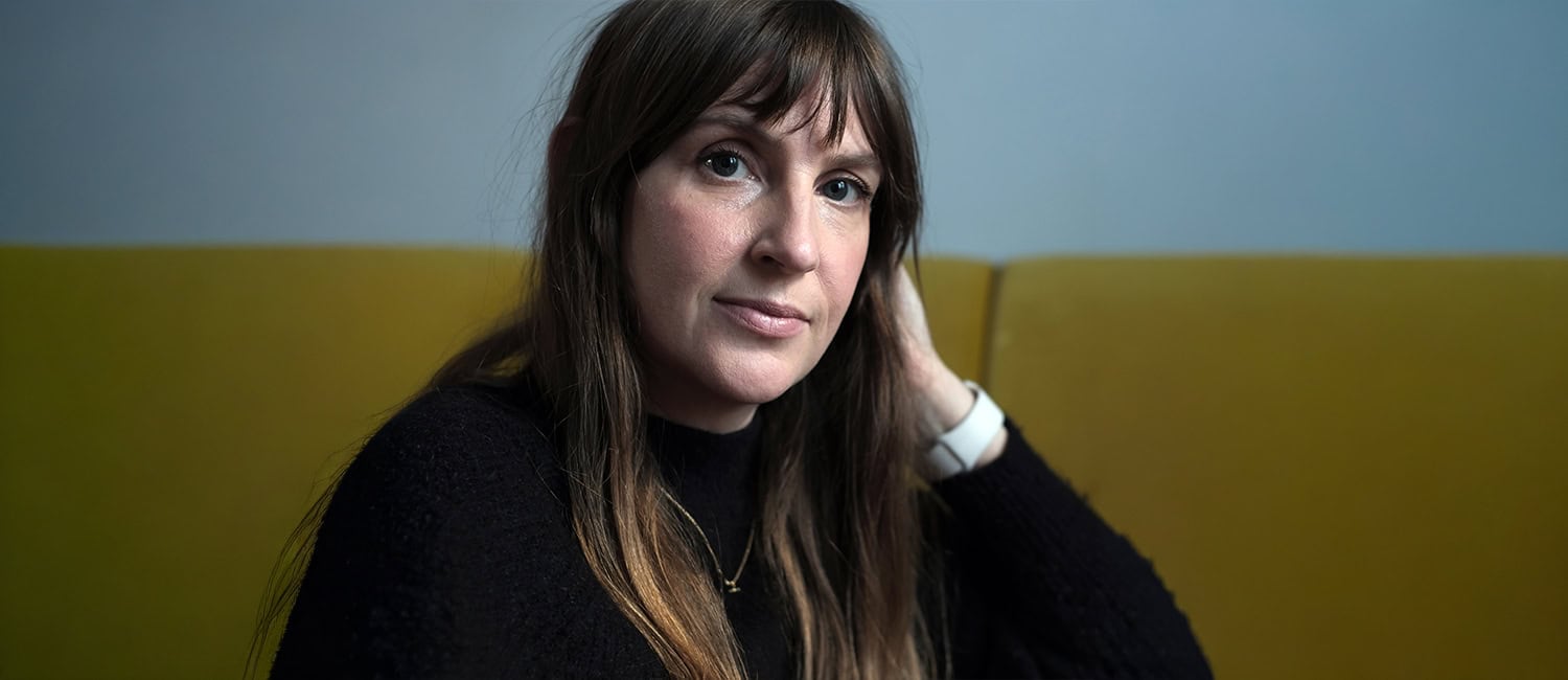 Claire Hopper, graphic design consultant and director at Claire Boston Ltd, seated on a yellow sofa