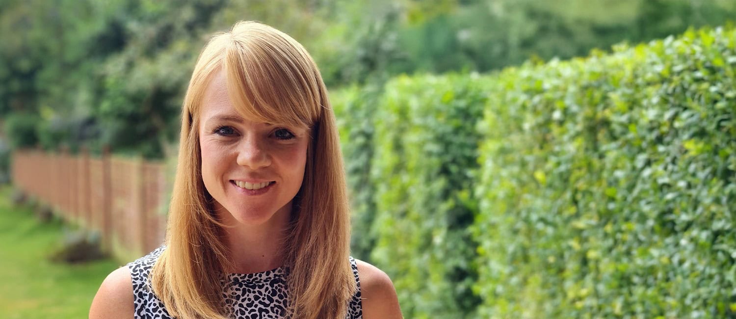 Robyn Schuleman, content writer and director at James and Joy Limited standing outdoors in front of a green hedge.