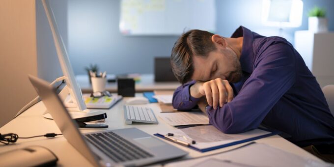 Office worker resting at desk with documents and computer, representing a company with no active business activity.