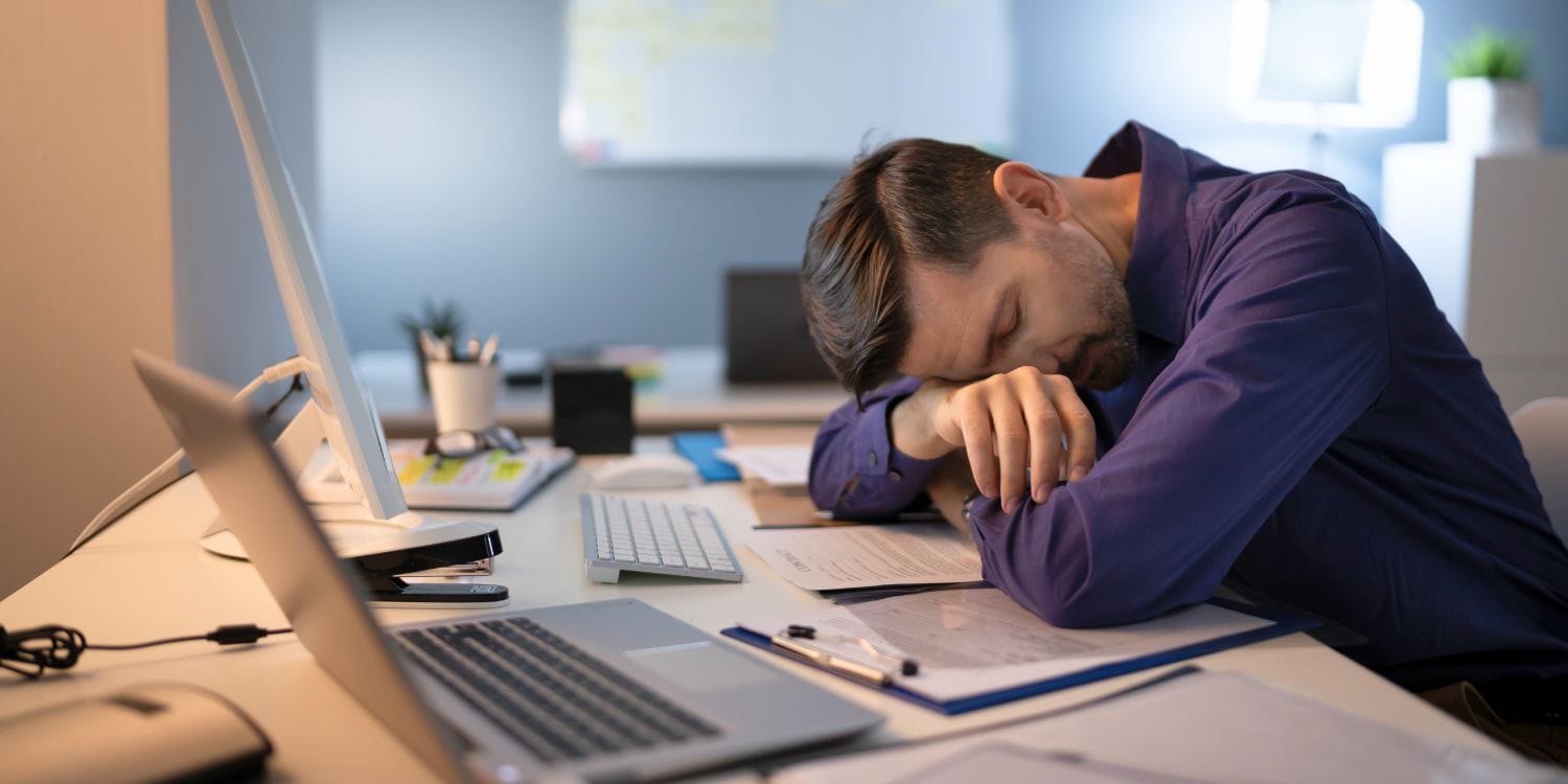Office worker resting at desk with documents and computer, representing a company with no active business activity.