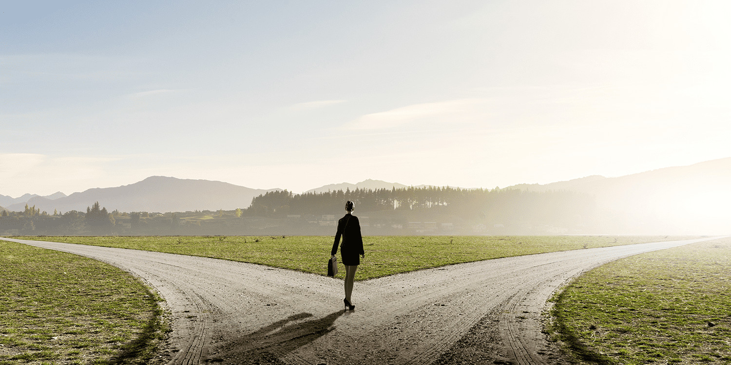 Woman standing in front of two roads that veer off in different directions, illustrating the choice of Limited or Ltd at the end of a company name.