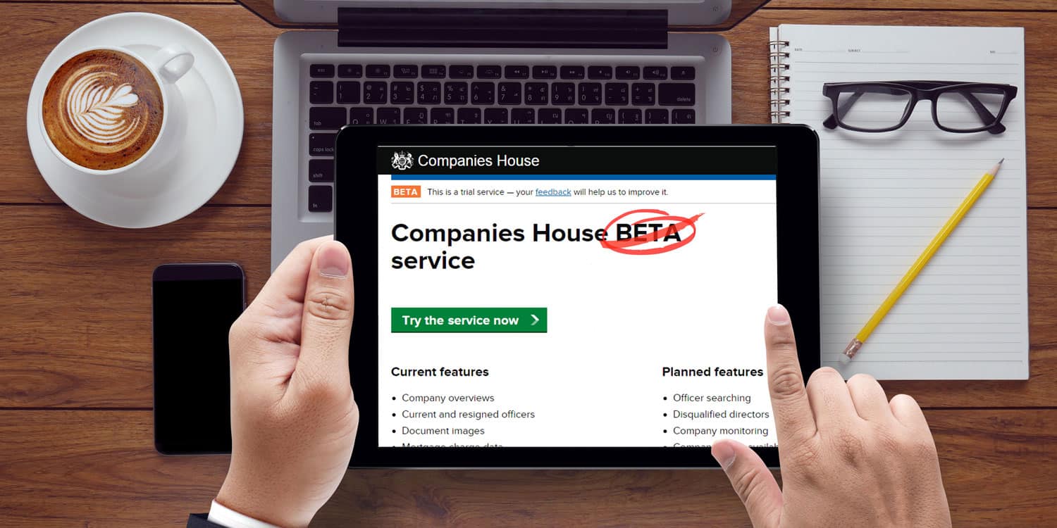 A business person holding an iPad displaying the new Company House Service with the old 'BETA' name scored out.