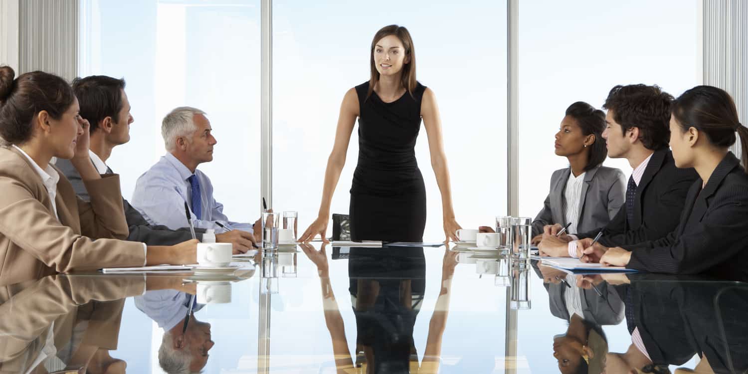 Photograph of a group of business men and women sitting around a large boardroom table, illustrating the concept of limited company meetings and resolutions