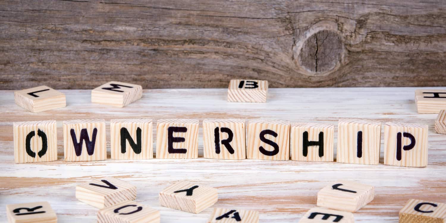 Wood blocks sitting on a table, displaying the word 'OWNERSHIP', illustrating the query pertaining to who owns a limited company.