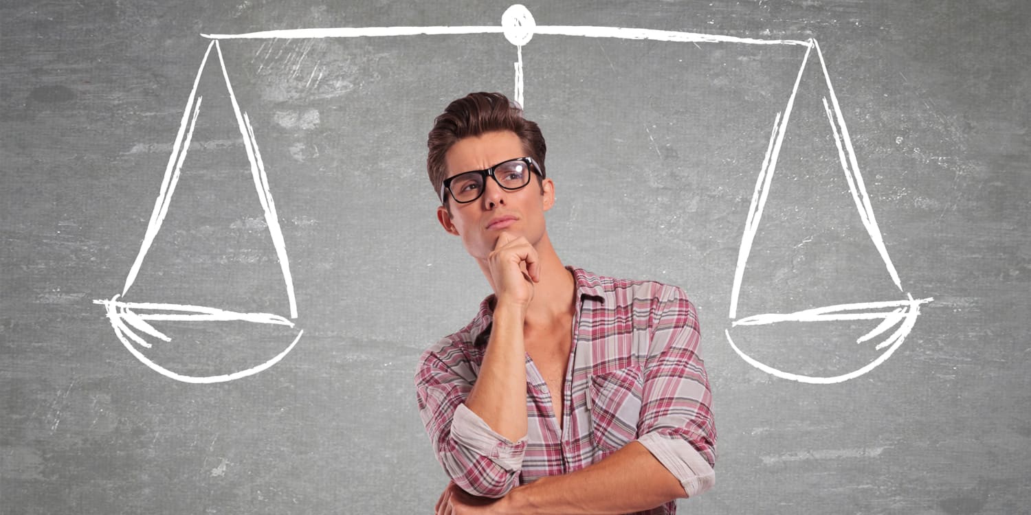Young man in red checked shirt, standing in front of a wall with a set of scales drawn on it, illustrating the concept of deciding choosing between a limited company or LLP.