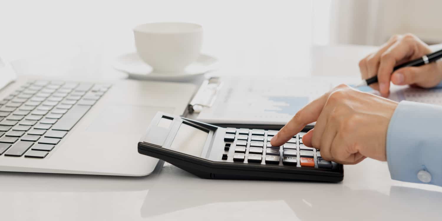 A business person working on company accounts and using a calculator.