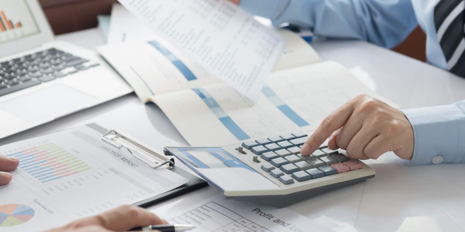 Business person working with a calculator with annual accounts documents on desktop.