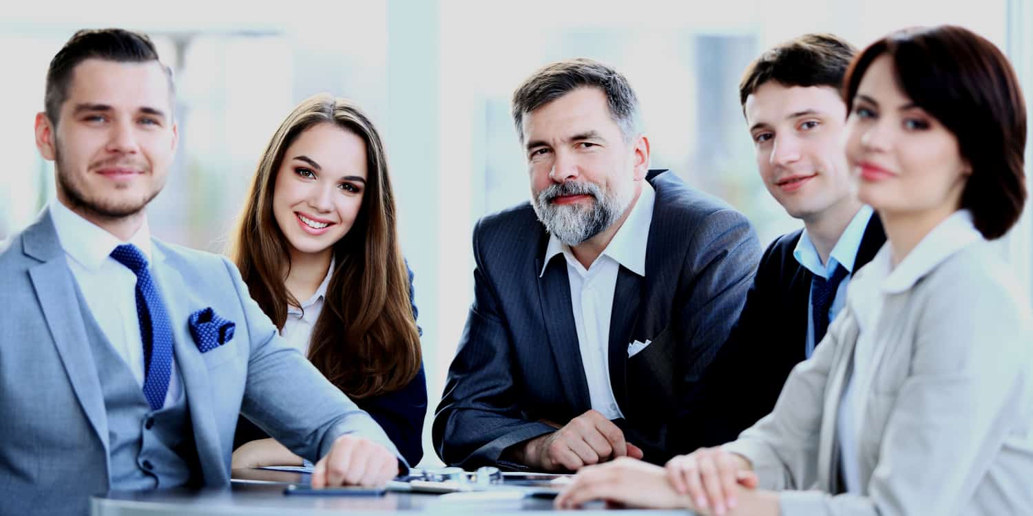 Picture of five individuals dressed in business attire, sitting around a table during a meeting, used as an example of limited company directors carrying out their collective duties.