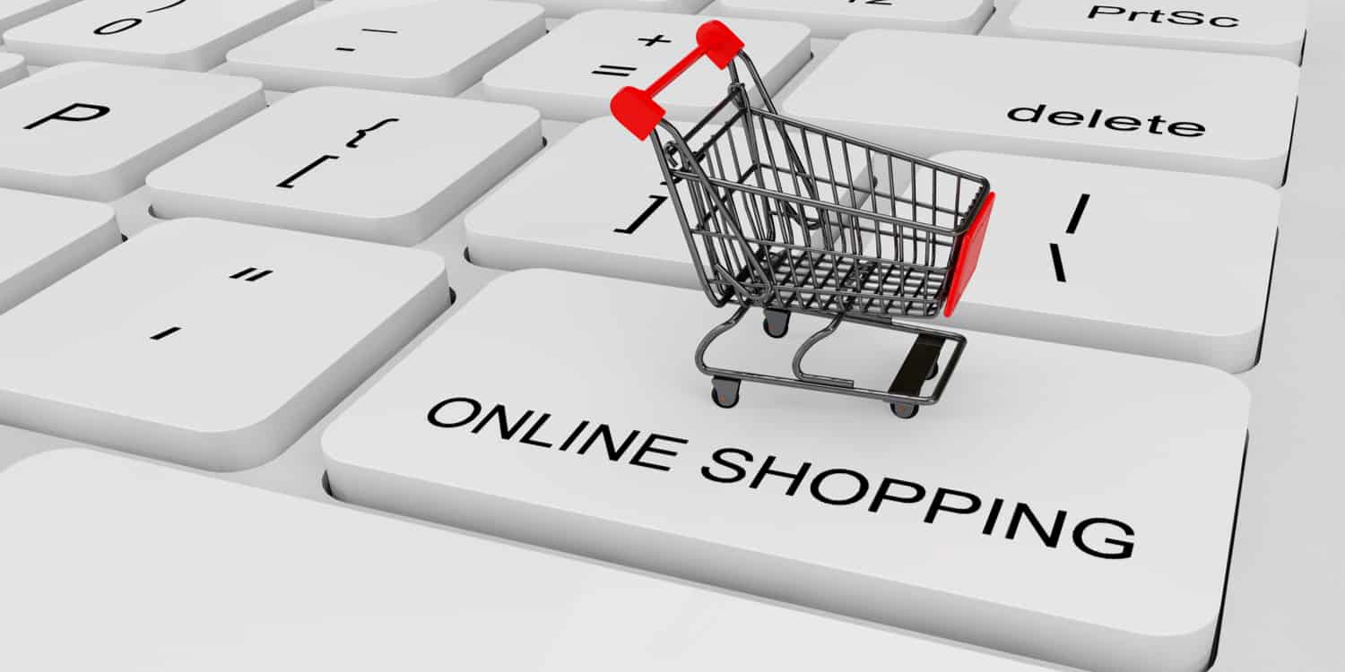 Miniature supermarket shopping trolley sitting on a laptop keyboard key labelled 'ONLINE SHOPPING' - illustrating the concept of an online business.
