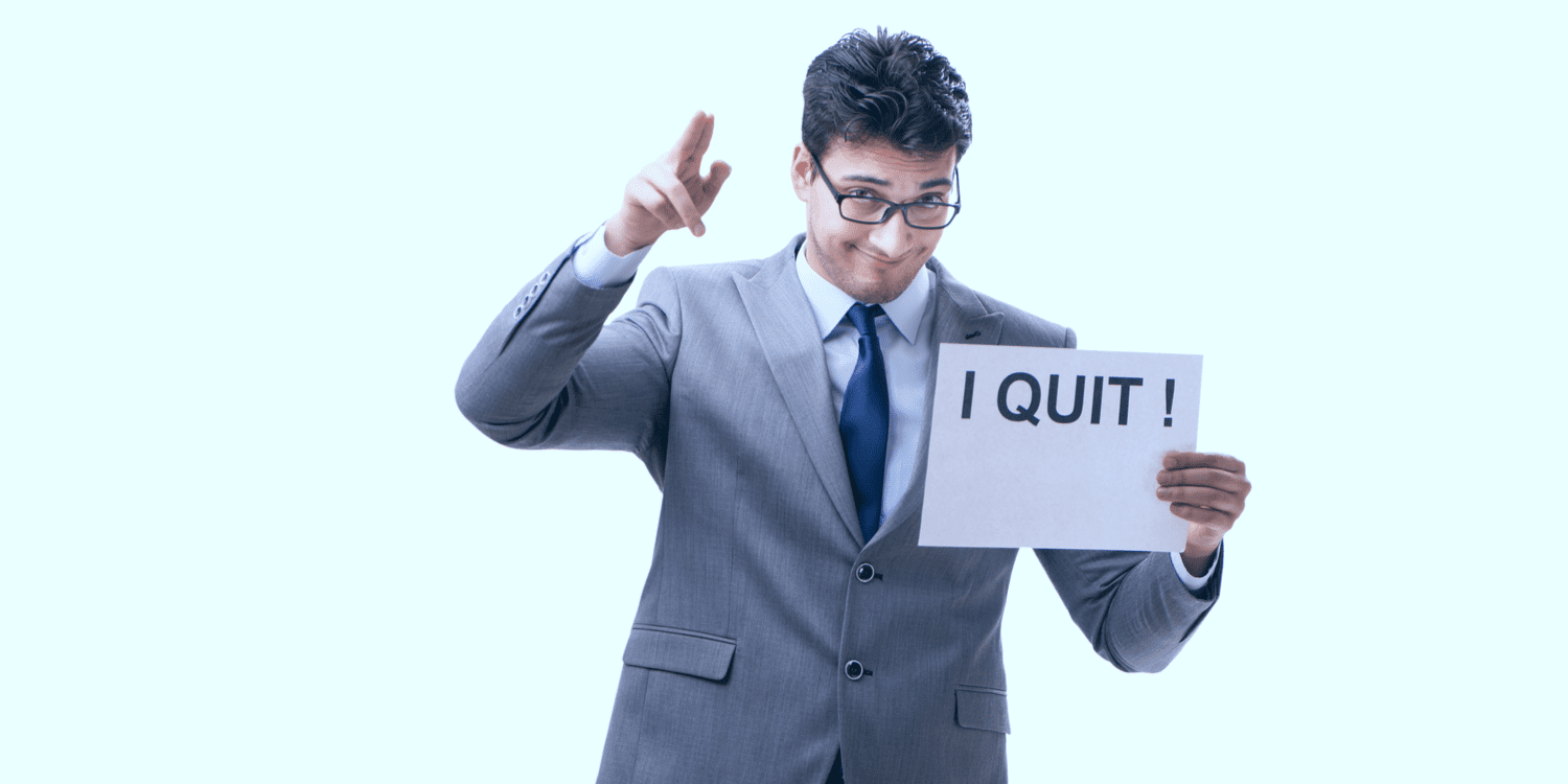 Company director in light grey suit with white shirt and dark blue tie, holding up a sign saying 'I QUIT'.