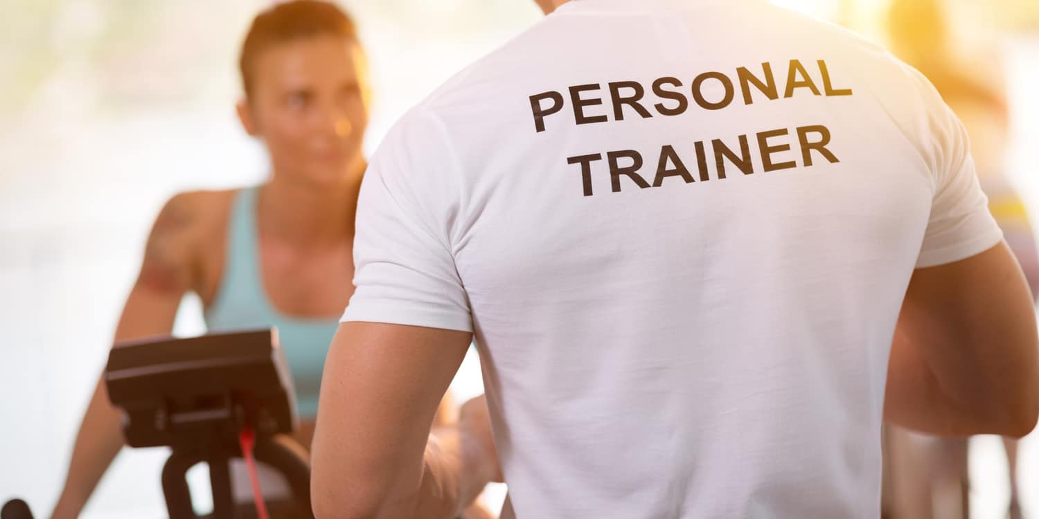 Personal trainer in white t-shirt on weights lifting training with client