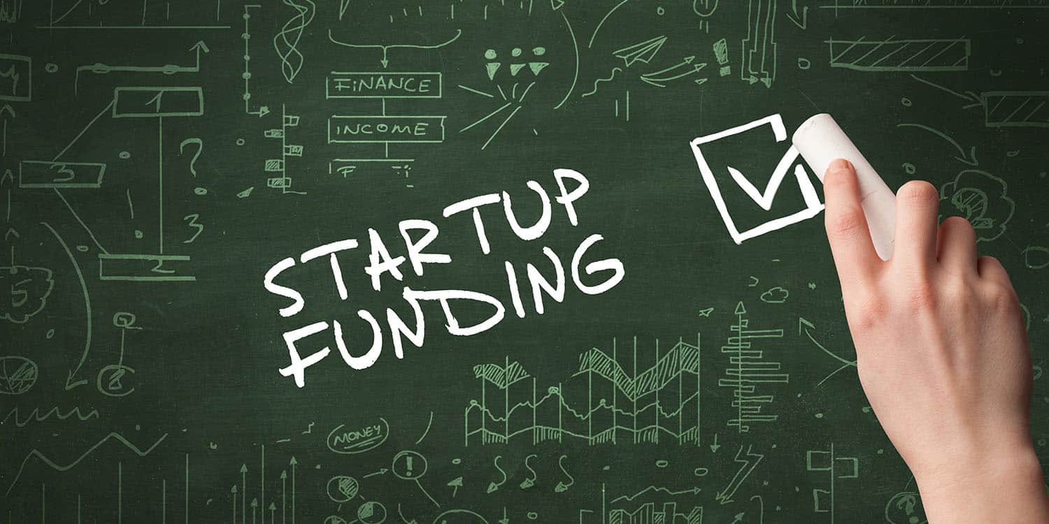 Hand drawing STARTUP FUNDING inscription with white chalk on blackboard,.