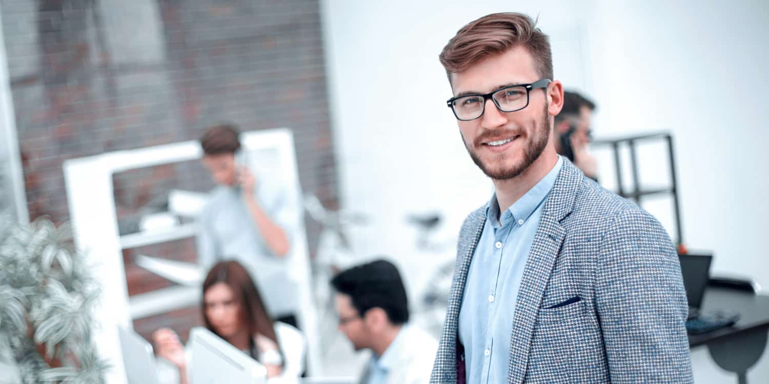 Modern young businessman with staff working in the background.