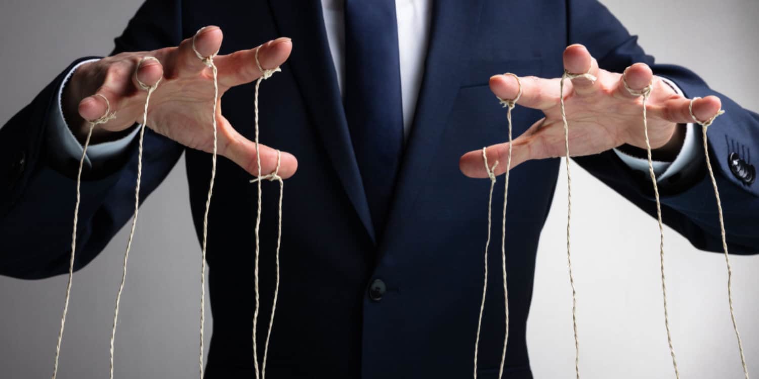 Businessman in blue suit with his fingers attached to puppet strings.