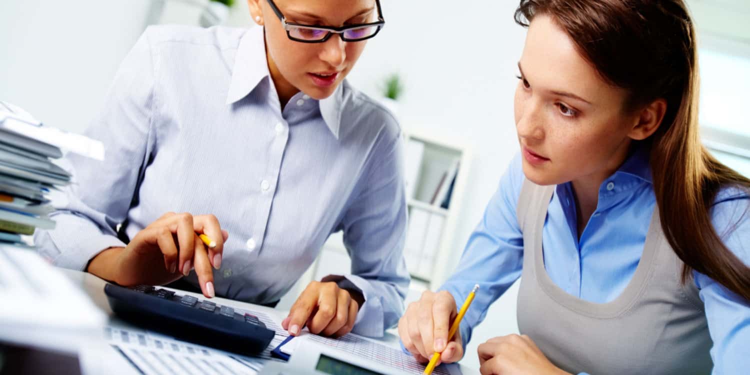 Portrait of two businesswomen working with annual accounts in an office.