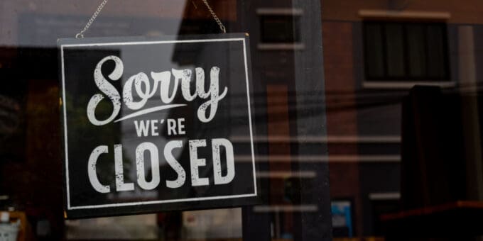 Vintage black and white retro 'Sorry We're Closed' sign on a coffee glass door.