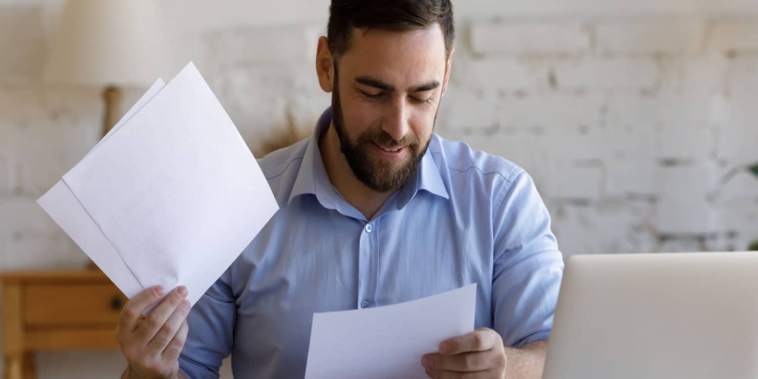 Smiling Scottish company director reviewing tax paperwork at home workplace.