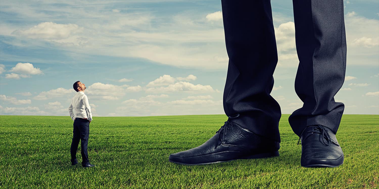 Image of businessman standing in a field next to a 'giant' businessman, representing a large corporation