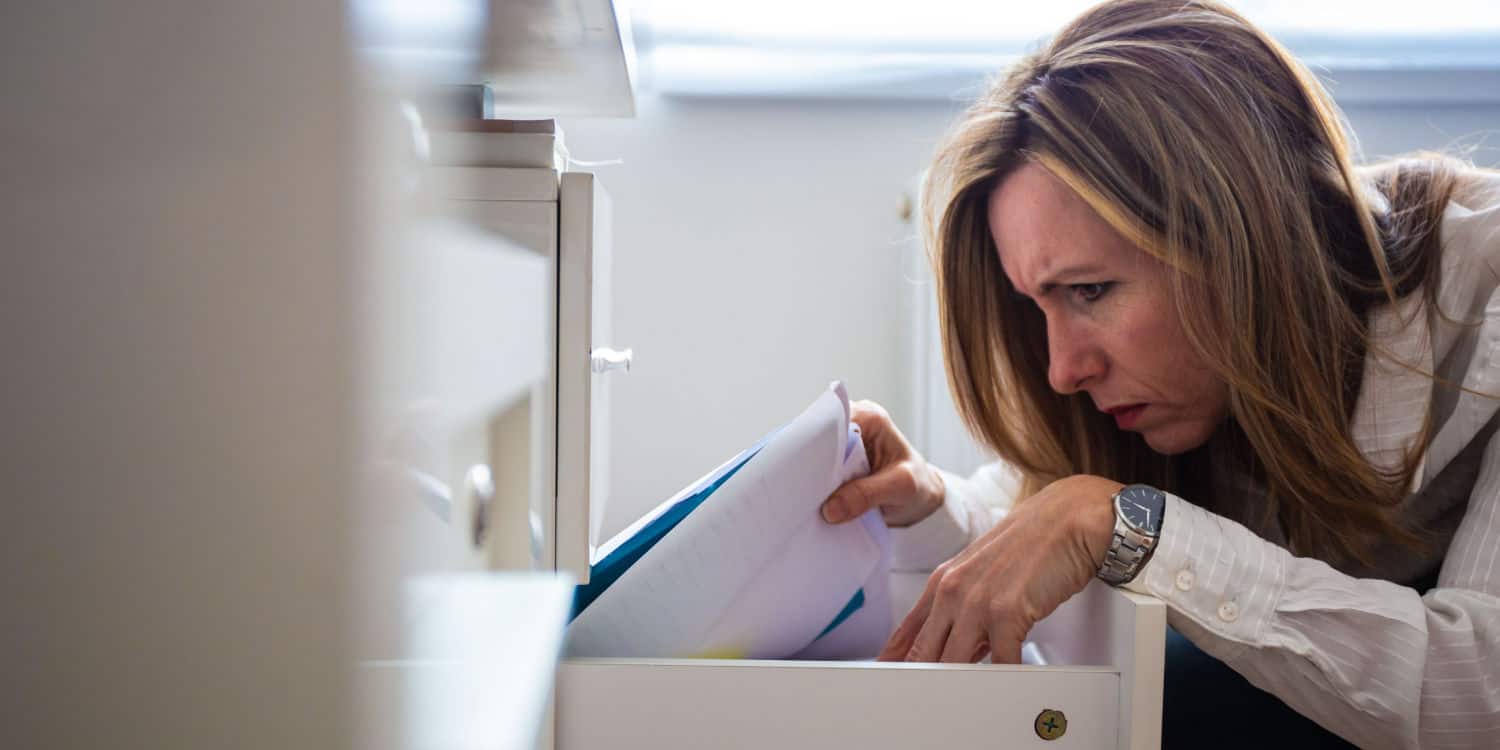 Female company director looking for lost memorandum and articles of association in an office filing cabinet.