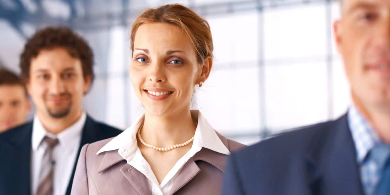 Young female company officer standing in the row of business people.