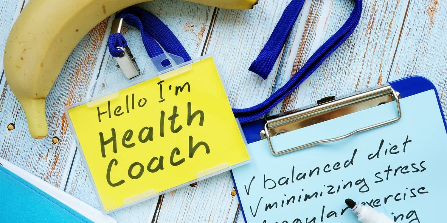 Health coach badge and check list with clipboard lying on wooden table.