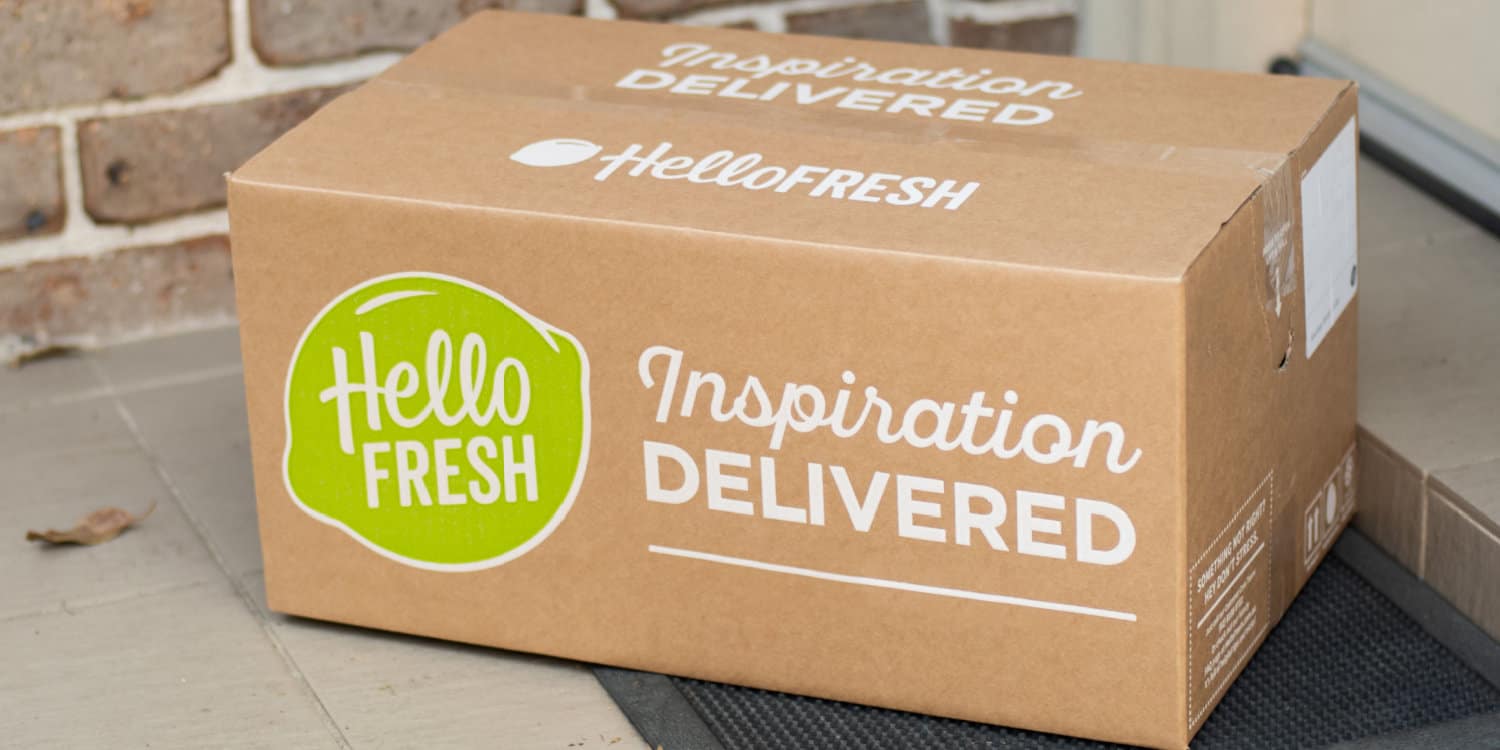 Hello Fresh meal kit in brown cardboard box sitting on the door step of a house - illustrating concept of a subscription box business.