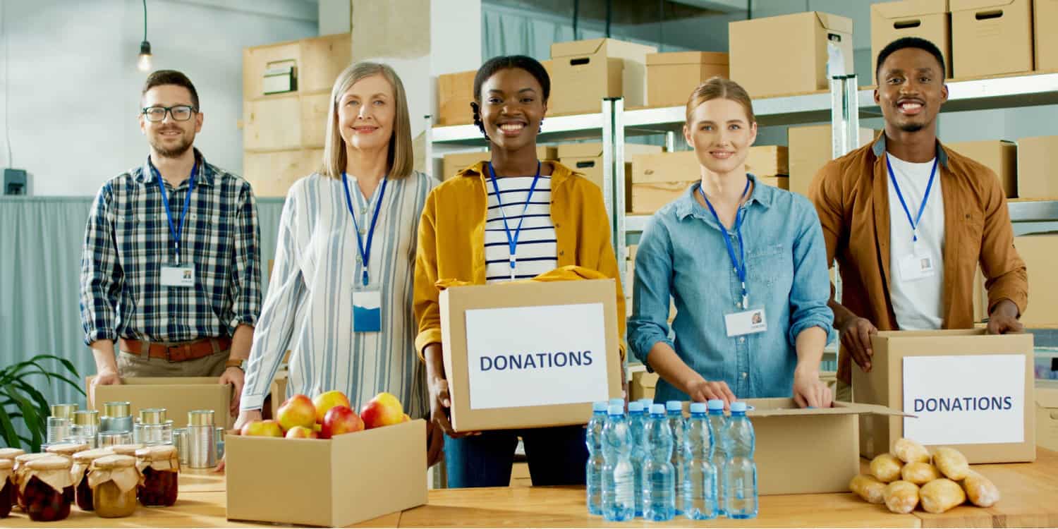 Cheerful charity company workers at a charity warehouse looking at camera and smiling.