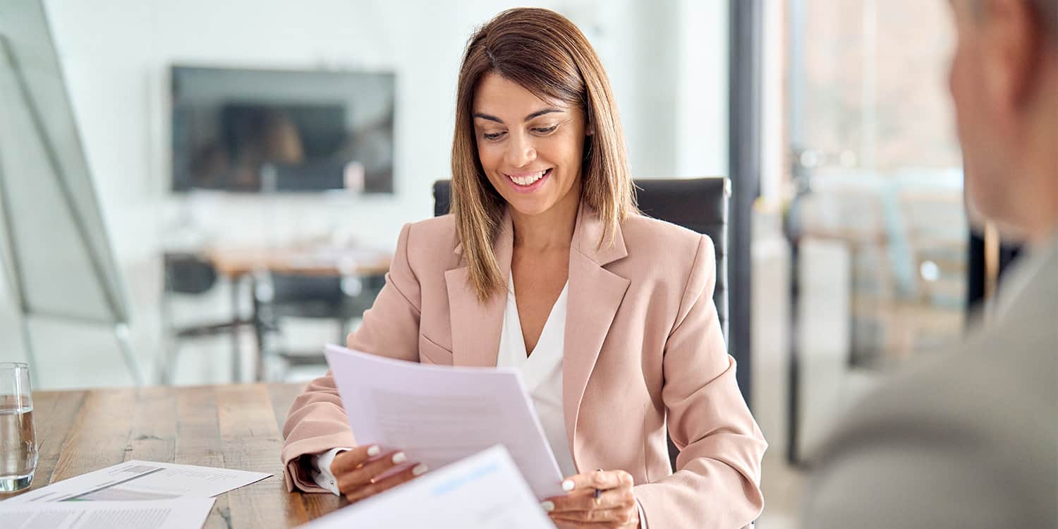 Image of smiling female business owner looking over documents representing the shareholders' agreement, with male colleague watching