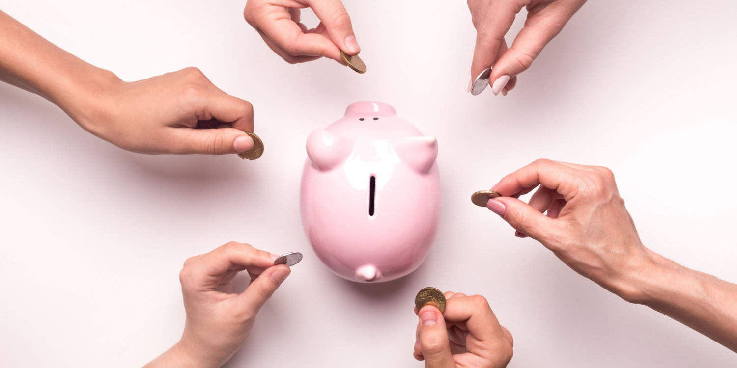 Hands throwing money into a pink piggy bank, illustrating the concept of buisness investment.