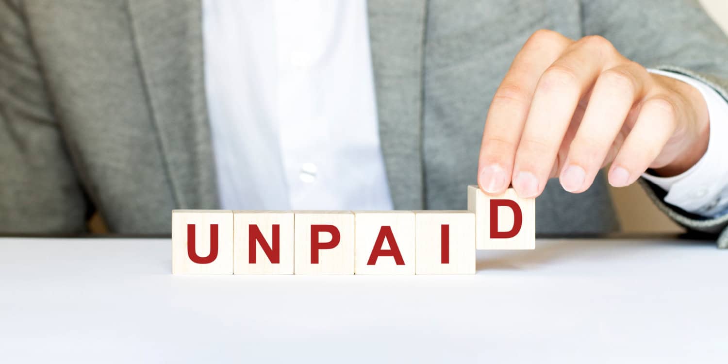 The word UNPAID made with wood building blocks, illustrating the concept of unpaid shares.