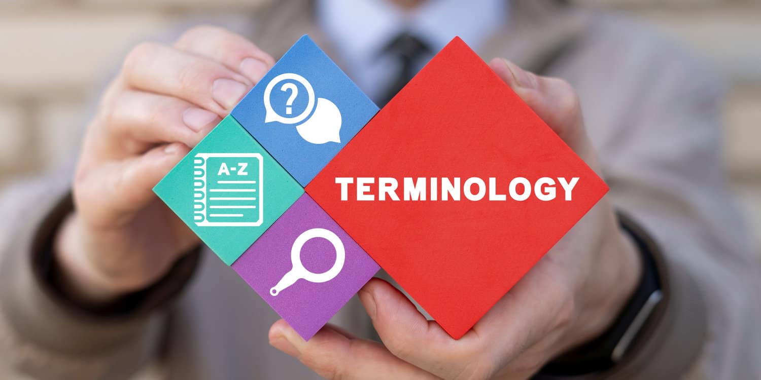 Hands holding coloured blocks displaying symbols and the word TERMINOLOGY. Concept of glossary of terms in finance, business, education and accounting.