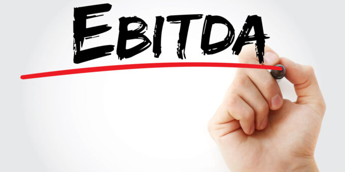 Hand writing EBITDA - Earnings Before Interest, Taxes, Depreciation and Amortization with marker pen on grey background.