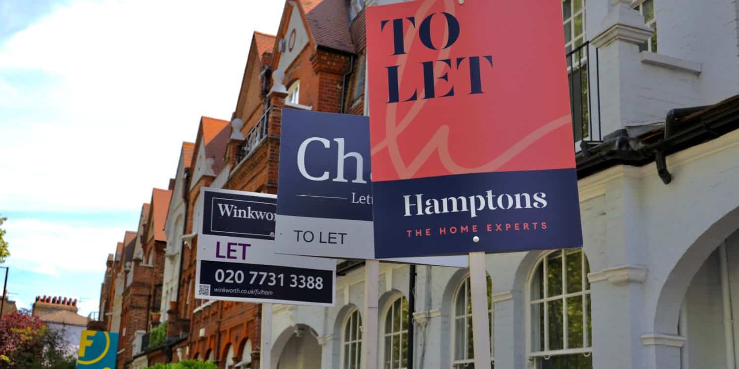 Real estate agent 'To let' signs in front of a row of terraced houses in London.