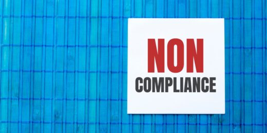 Blank note pad with NON COMPLIANCE text on blue wooden background.