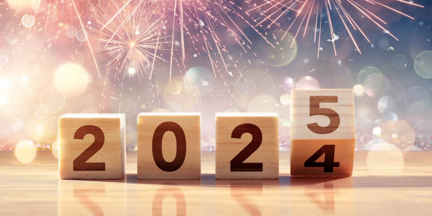 Blocks with numbers showing "2024" and the "4" is falling over to show "2025". The background shows fireworks, symbolising the beginning of your business resolutions.