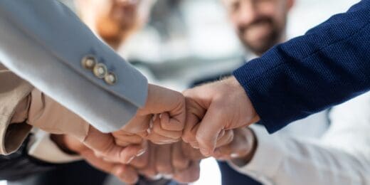 A group of diverse hands engaging in a fist bump, symbolising teamwork and collaboration in a professional setting.