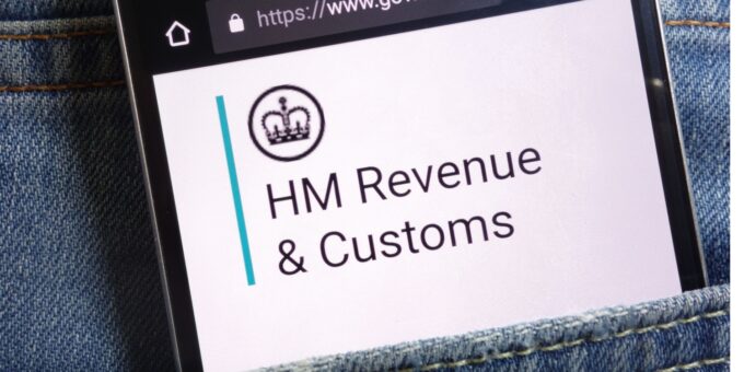 The UK government website for HM Revenue and Customs displayed on smartphone hidden in jeans pocket.