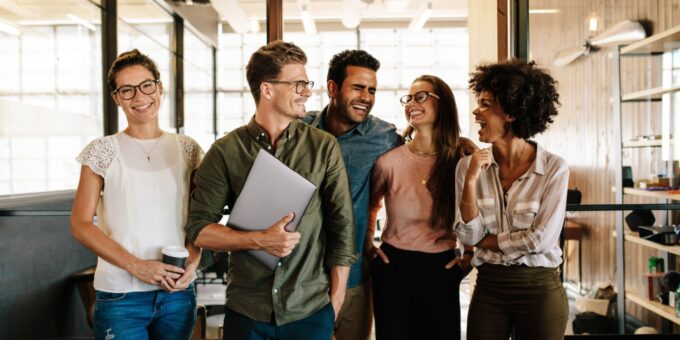 Group of diverse colleagues smiling and interacting in a modern workplace, reflecting strong cultural intelligence and inclusive team dynamics