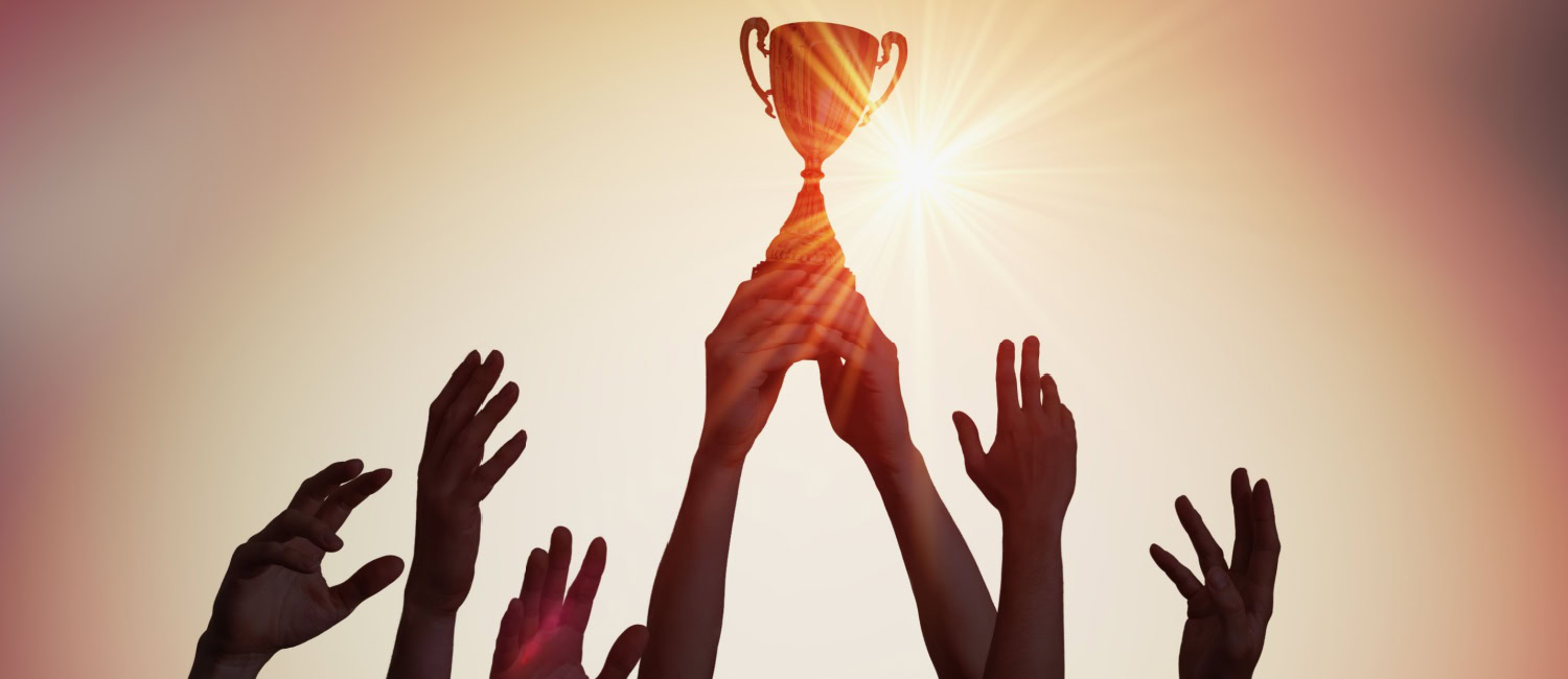 Image of a team’s hands holding up a trophy.