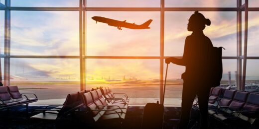 Silhouette of a traveler with a suitcase at an airport watching a plane take off during sunset, symbolising the journey and new opportunities to start a business abroad