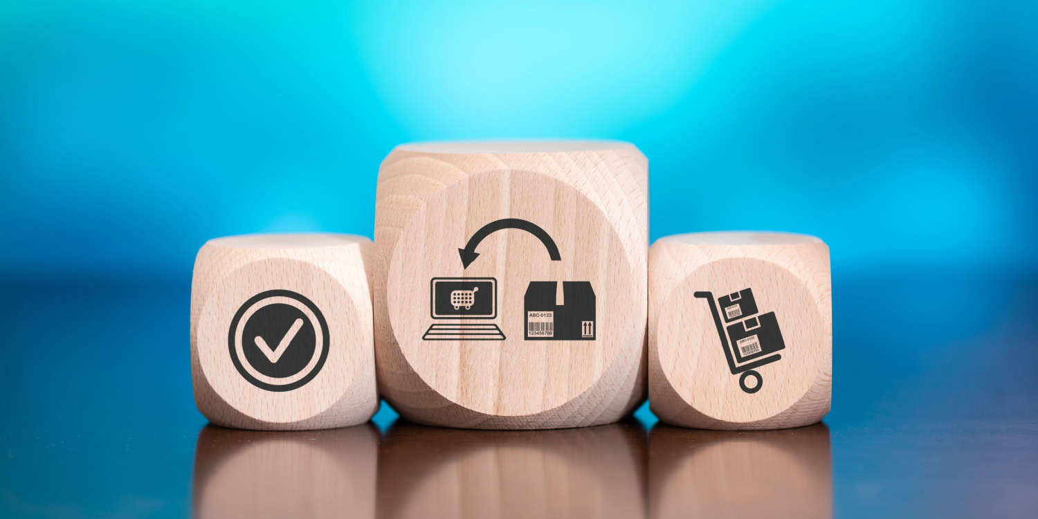 Wooden blocks displaying icons of a checkmark, an online store connected to a warehouse, and a delivery cart, representing the concept and process of dropshipping