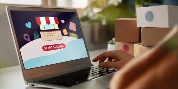 Person using a laptop with a screen that reads "Start Selling" and shows a storefront graphic, representing the setup of an ecommerce platform for online selling