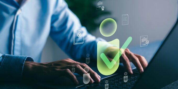 Person typing on a laptop with digital verification icons floating on screen, representing the process of Companies House identity verification for UK directors and PSCs