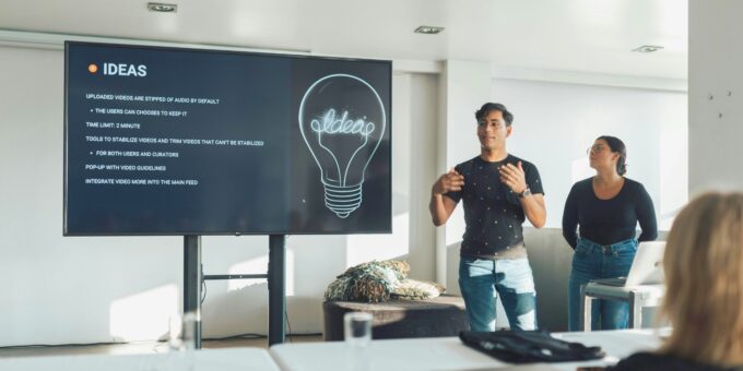People presenting business idea on screen with lightbulb graphic during team meeting