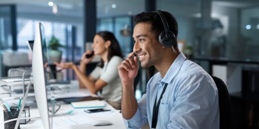 Smiling customer service adviser wearing a headset at a computer, representing an Authorised Corporate Service Provider (ACSP) helping a client with company formation.