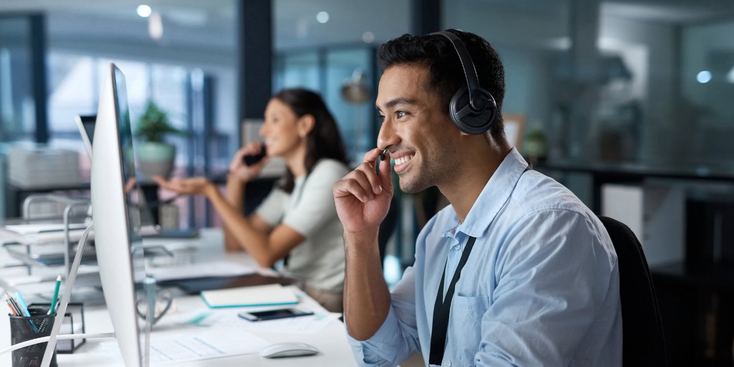 Smiling customer service adviser wearing a headset at a computer, representing an Authorised Corporate Service Provider (ACSP) helping a client with company formation.
